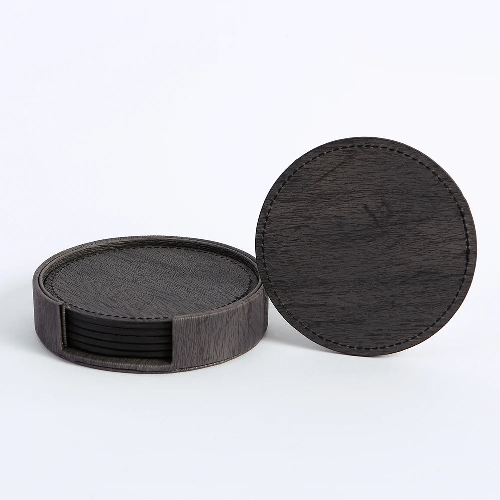 Ensemble de sous-verres ronds en bois foncé avec bords en cuir, empilés et prêts à être utilisés.