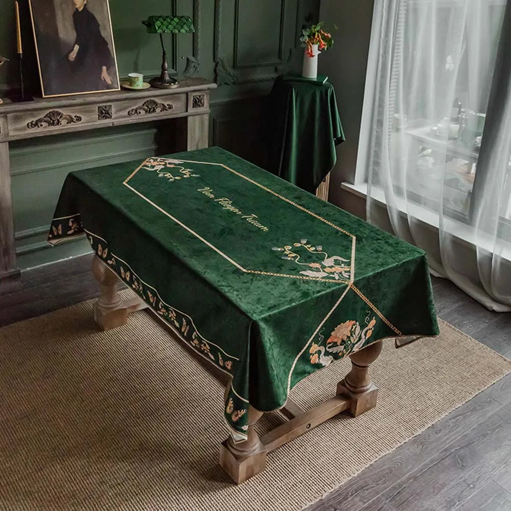 Lit de funérailles recouvert d'un drap vert foncé orné de motifs dorés, placé dans une pièce sombre et meublée avec un style ancien.