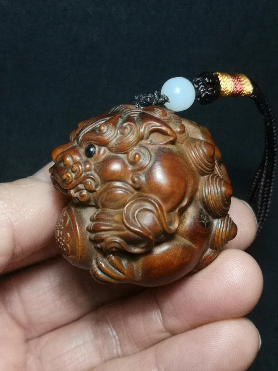 pendentif sculpté lion globe caractères chinois motifs floraux artisanal traditionnel yeux noirs