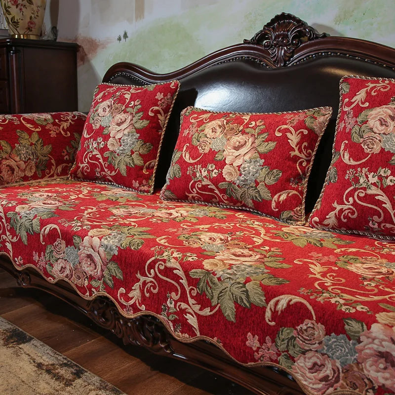 Canapé vintage en bois foncé avec un motif floral rouge, vert et beige sur les coussins, créant une atmosphère élégante et chaleureuse dans la pièce.
