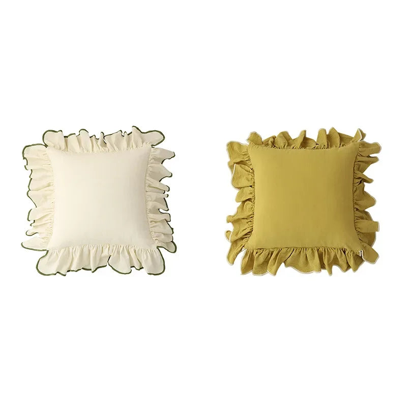Deux coussins décoratifs carrés avec des volants, l'un de couleur crème et l'autre de couleur jaune moutarde.