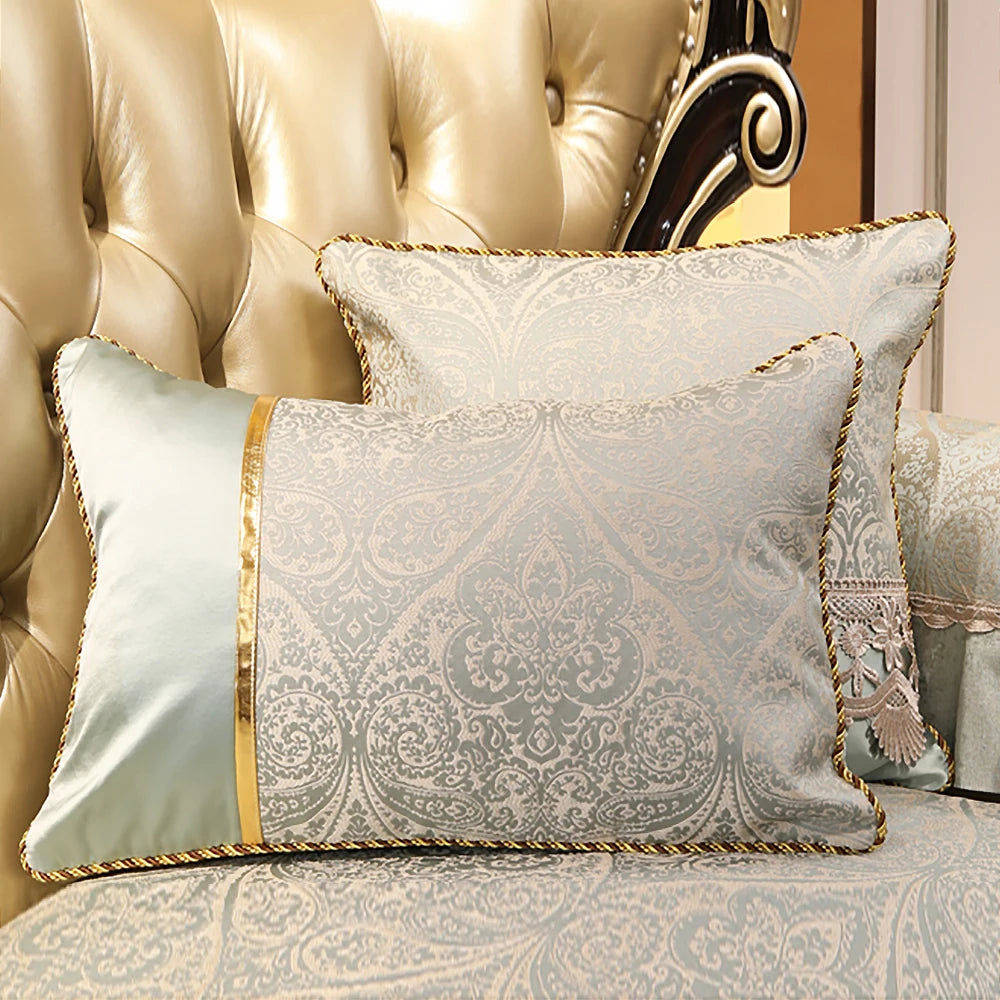 Cette image montre un oreiller décoratif orné d'un motif d'arabesques élégant et de couleurs neutres, posé sur un canapé en cuir beige.