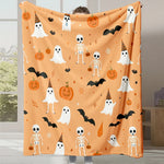 Une couverture d'Halloween aux motifs de fantômes, de squelettes, de chauves-souris et de citrouilles sur un fond orange.