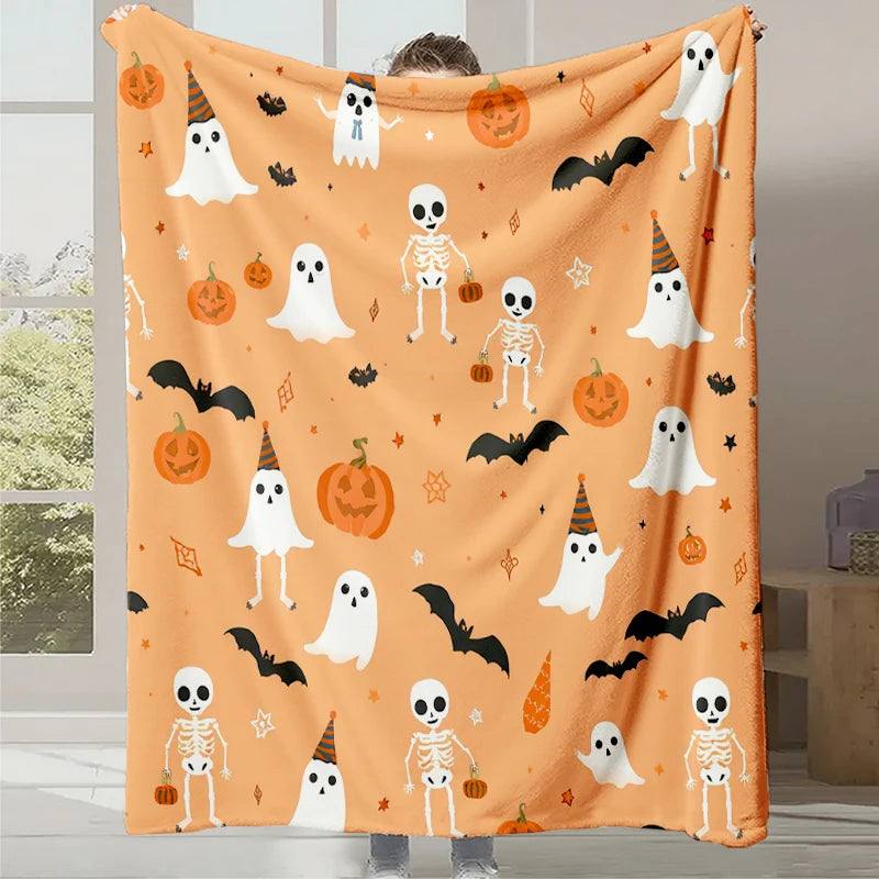 Une couverture d'Halloween aux motifs de fantômes, de squelettes, de chauves-souris et de citrouilles sur un fond orange.