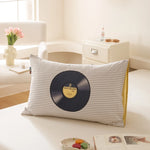 Un oreiller décoratif avec une impression de disque vinyle, inspirant une ambiance chaleureuse et musicale dans la pièce.