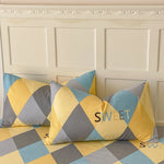 Coussins multicolores motif géométrique sur fond de mur décoré de moulures, créant une ambiance chaleureuse et moderne.