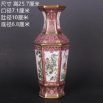 Un magnifique vase de porcelaine chinoise orné de motifs floraux et de paysages peints de manière détaillée et colorée sur un fond rose.