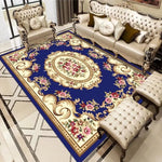 Un luxueux salon décoré avec un élégant canapé en cuir capitonné, un magnifique tapis bleu foncé orné de motifs floraux et dorés, ainsi que des fauteuils assortis, créant une atmosphère sophistiquée et chaleureuse.