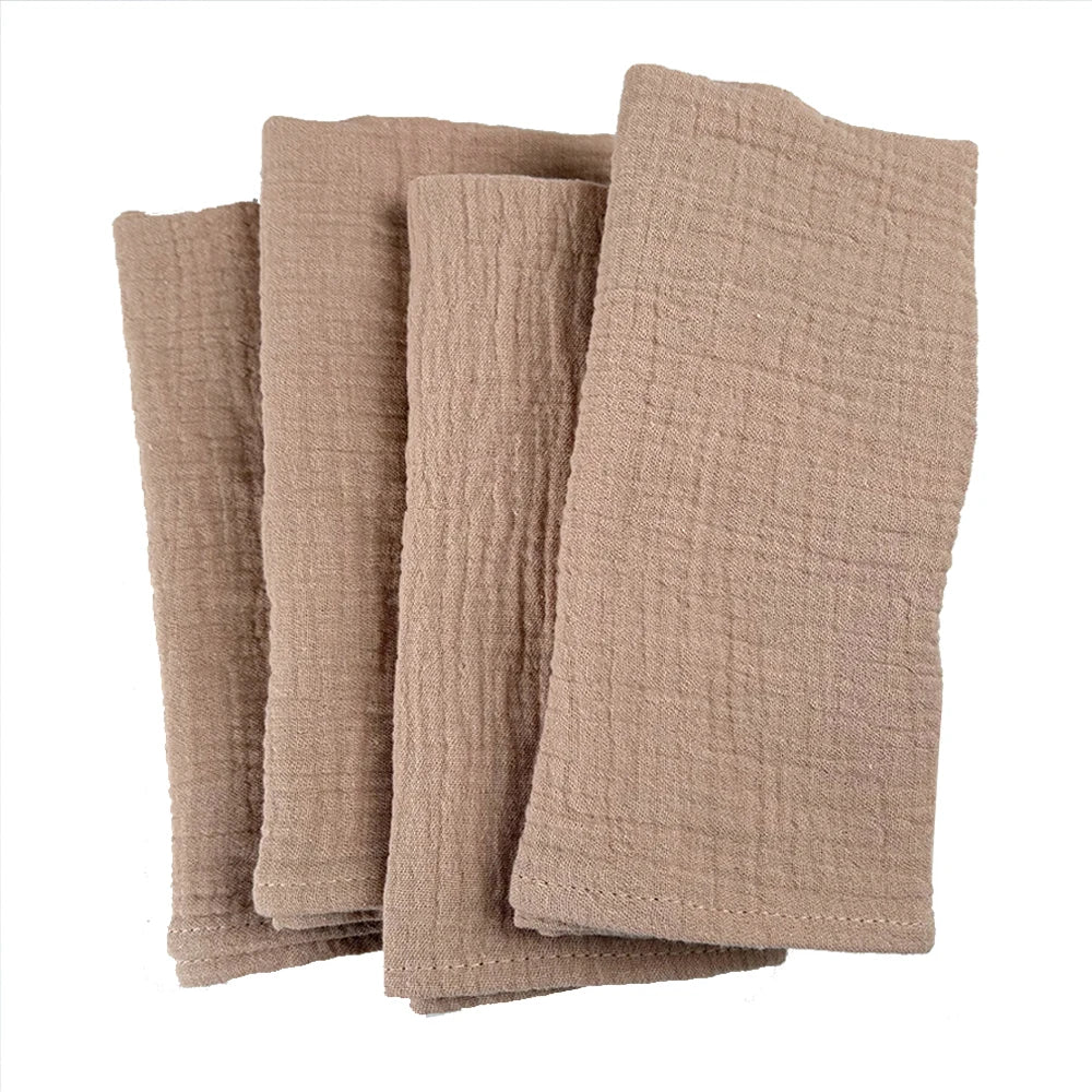 Serviettes de table en lin beige empilées sur fond blanc.