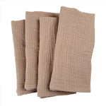 Serviettes de table en lin beige empilées sur fond blanc.