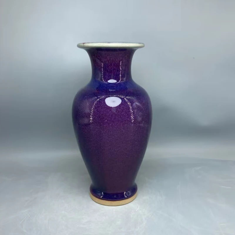 Un élégant vase en céramique de couleur violette foncée, avec une forme effilée et un design distinctif.