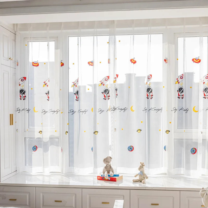 Voilage pour chambre d'enfant avec motifs d'espace, fusées et étoiles, apportant une ambiance ludique et éducative. Parfait pour les jeunes explorateurs passionnés par l'univers et les aventures spatiales. Idéal pour décorer la fenêtre d'une chambre tout en maintenant une luminosité agréable.