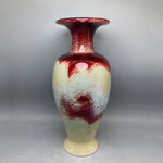 Un vase décoratif de couleur crème et rouge, avec des motifs abstraits, créant une atmosphère élégante et artistique.
