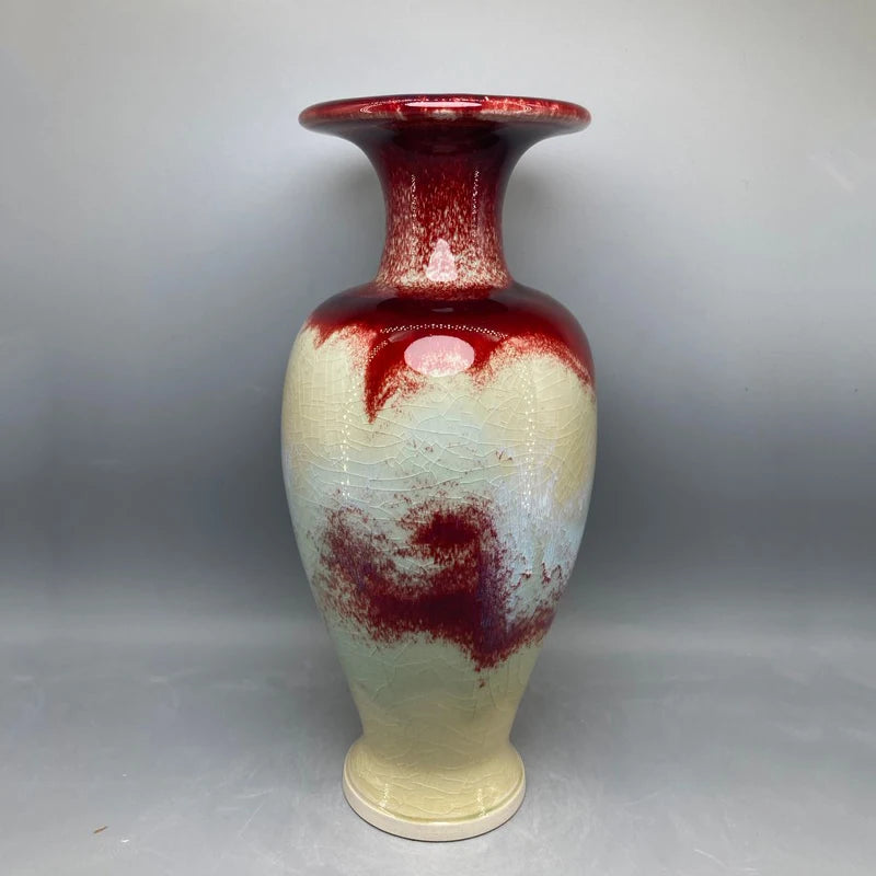Un vase décoratif de couleur crème et rouge, avec des motifs abstraits, créant une atmosphère élégante et artistique.