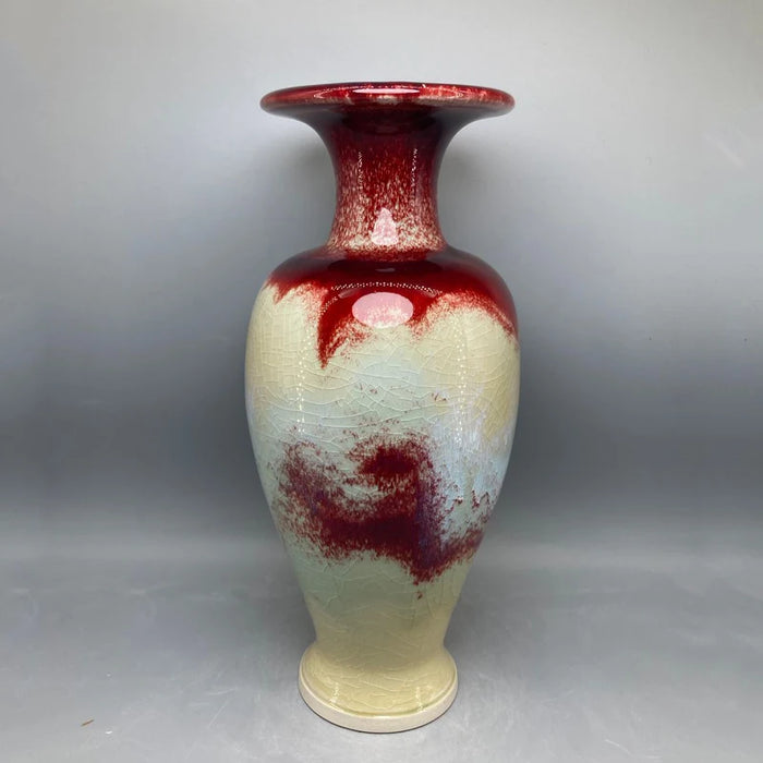 Un vase décoratif de couleur crème et rouge, avec des motifs abstraits, créant une atmosphère élégante et artistique.