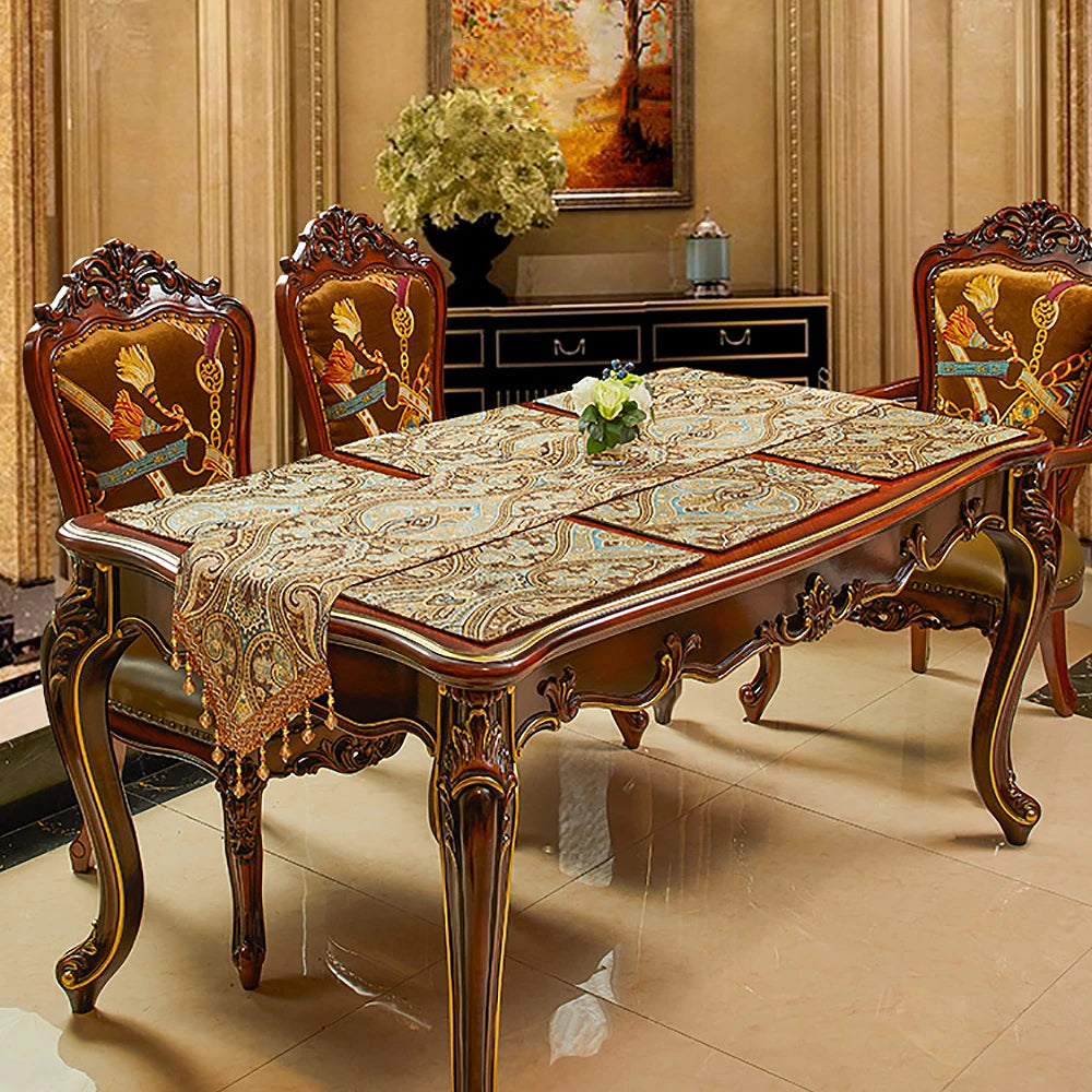 Une table de salle à manger de style riche avec des chaises sculptées et une nappe ornée, placée dans une pièce élégante avec un tableau encadré au mur.