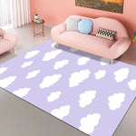 Cette image représente un intérieur chaleureux et douillet, avec un canapé rose pastel et des coussins colorés. Le sol est recouvert d'un tapis violet clair décoré de nuages blancs, créant une ambiance apaisante et nuageuse.