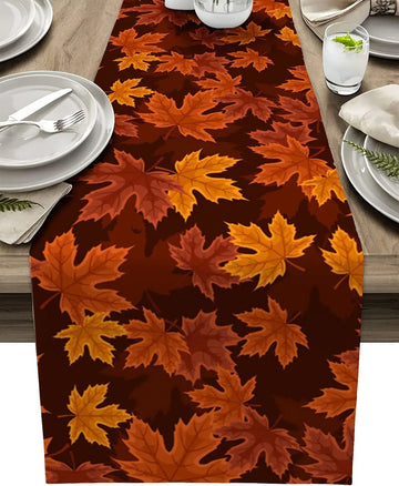 Un chemin de table recouvert de feuilles d'érable automnales dans des tons de rouge, d'orange et de jaune, créant une atmosphère chaleureuse et saisonnière.