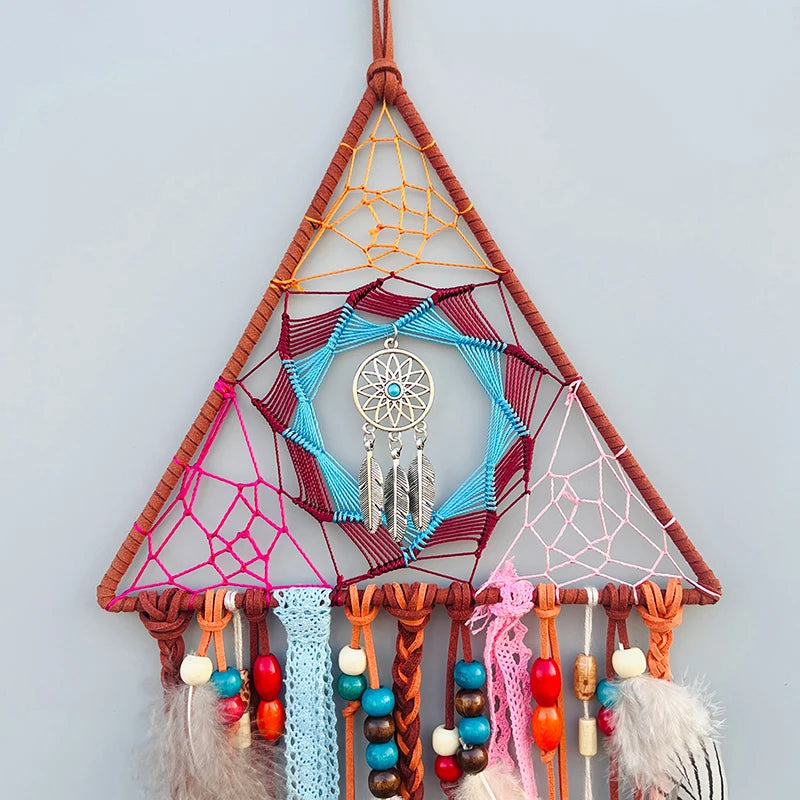 Une captivante décoration murale colorée en forme de triangle suspendue par des cordes, ornée d'un attrapeur de rêves et de perles multicolores.