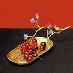 Élégante assiette dorée présentant une branche avec de jolies fleurs violettes et de délicieuses cerises rouges, accompagnée d'un bel oiseau doré posé sur le côté.