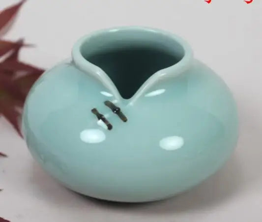 Un vase en céramique de couleur vert pastel avec des détails noirs.