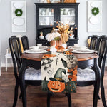 Un somptueux intérieur de salle à manger décoré avec soin pour la saison d'Halloween, mettant en scène une table ornée de motifs et accessoires thématiques, accompagnée d'un élégant vaisselier noir rempli de porcelaine blanche.