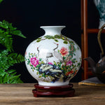 Magnifique vase en porcelaine blanche décoré de magnifiques grues, de fleurs roses épanouies et de verdure luxuriante, créant une scène naturelle apaisante.