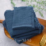 Serviette de bain bleu marine de marque Tian Mi Mi, empilée sur un plateau en bois, avec une fourchette en métal visible.