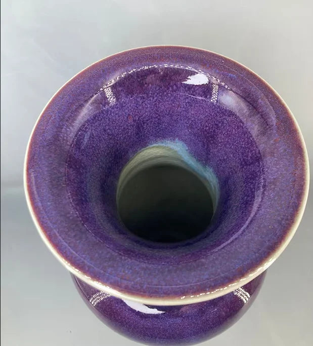 Un vase de céramique de couleur pourpre brillante avec un design élégant.