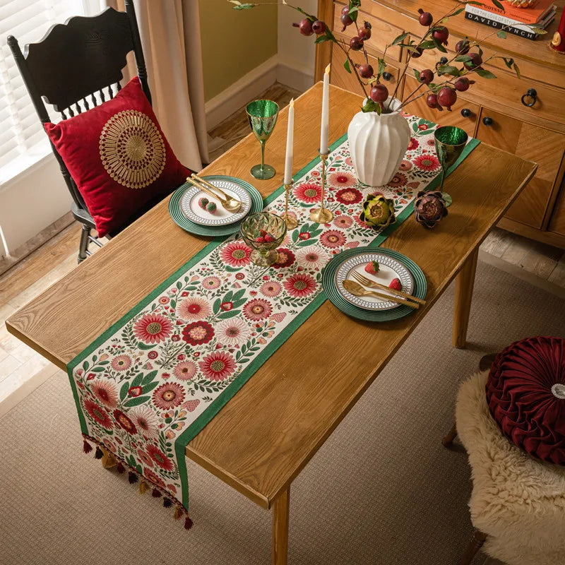 Une table à dîner colorée, avec un chemin de table fleuri, des assiettes vertes et des accessoires décoratifs, créant une ambiance chaleureuse et conviviale.