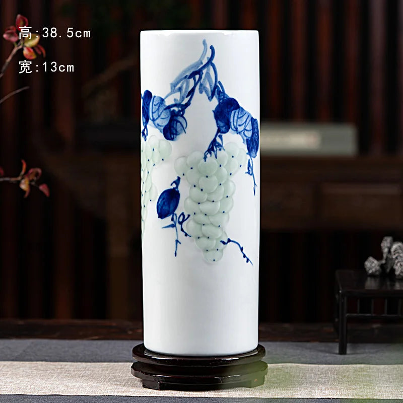 Vase cylindrique orné de motifs floraux bleus et blancs représentant des raisins sur fond blanc.