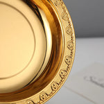 Un plat en porcelaine dorée aux motifs décoratifs élégants, avec un bord orné de fleurs et de lignes verticales.