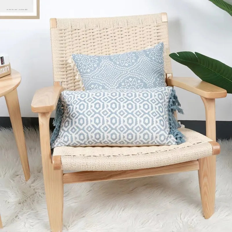 Un fauteuil en rotin naturel avec des coussins bleus ornés de motifs géométriques, installé dans un intérieur lumineux et apaisant.