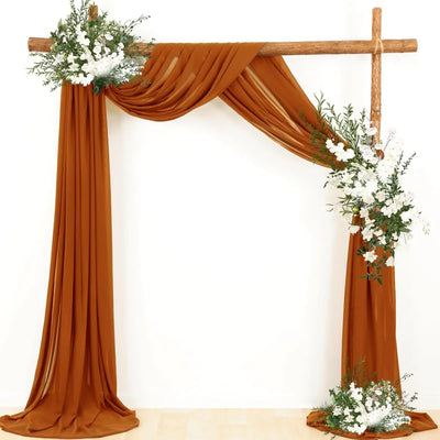 Rideau en mousseline de soie rouille drapé sur un arc de mariage