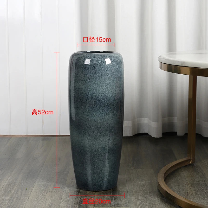 Un grand vase gris décoratif de 52 cm de hauteur et 15 cm de diamètre, posé sur un sol en bois.