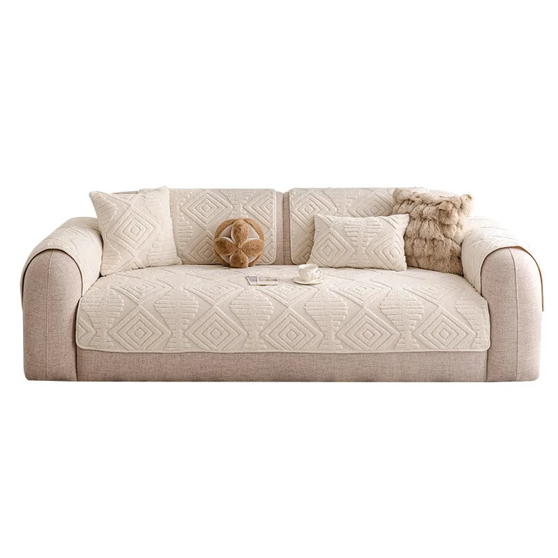 Canapé beige confortable avec motifs géométriques, décoré de coussins et d'un plaid en fourrure, une tasse sur la table basse.