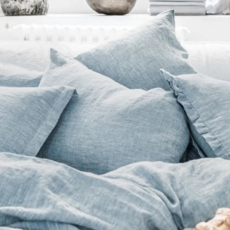 Coussins gris en lin froissé, créant une atmosphère cocooning et naturelle dans une pièce.