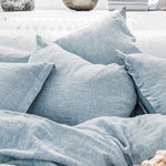 Coussins gris en lin froissé, créant une atmosphère cocooning et naturelle dans une pièce.