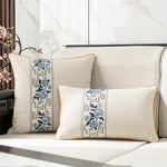 Deux oreillers décoratifs avec motifs floraux bleus et blancs sur un canapé dans un intérieur élégant.