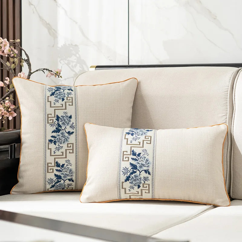 Deux oreillers décoratifs avec motifs floraux bleus et blancs sur un canapé dans un intérieur élégant.