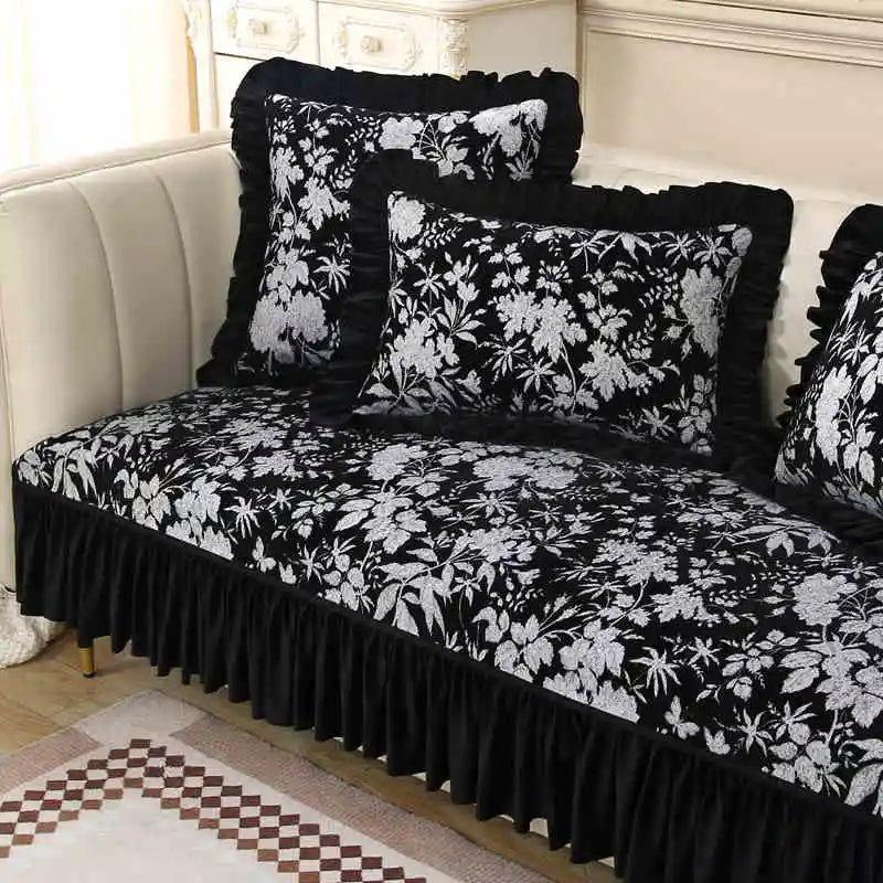 Un ensemble de literie élégant aux motifs floraux noirs et blancs, composé d'un drap-housse, de coussins décoratifs et d'une jupe de lit, créant une ambiance raffinée et chic dans la chambre.