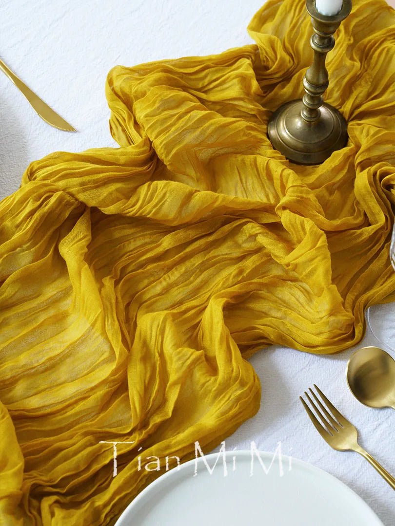 Une nappe de soie jaune vif, ornée d'un candélabre en laiton, est accompagnée d'une assiette blanche et de couverts dorés, créant une atmosphère chaleureuse et élégante.