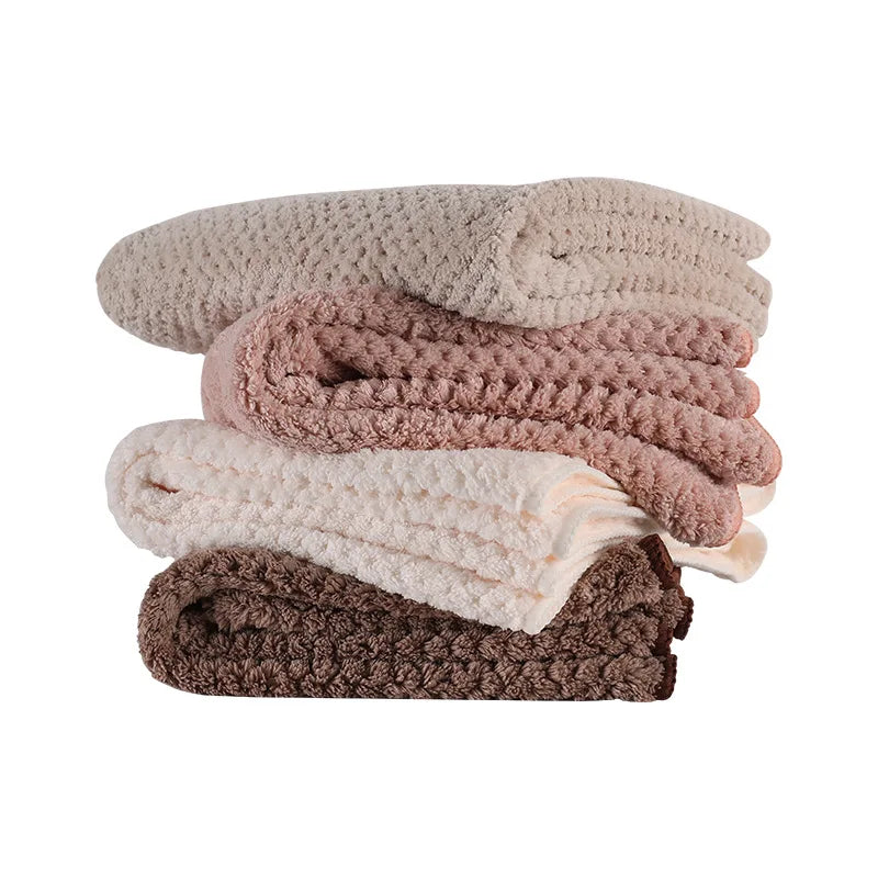 Pile de couvertures douces et moelleuses dans des tons de beige, rose et marron, offrant une texture agréable et une apparence accueillante.
