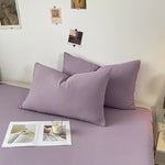 Chambre cosy avec coussin violet et design minimaliste.