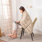 Une jeune femme se concentre profondément sur son ordinateur portable, enveloppée dans une couverture douillette, profitant du confort et de la tranquillité de son domicile.