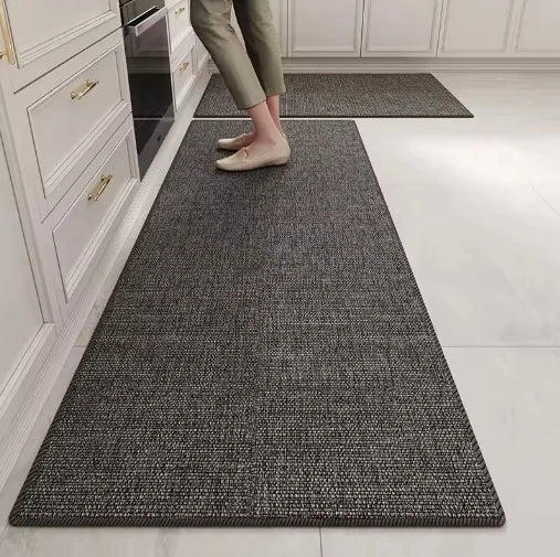 Un tapis gris motif tissé au sol d'une cuisine, avec des pieds nus posés dessus.