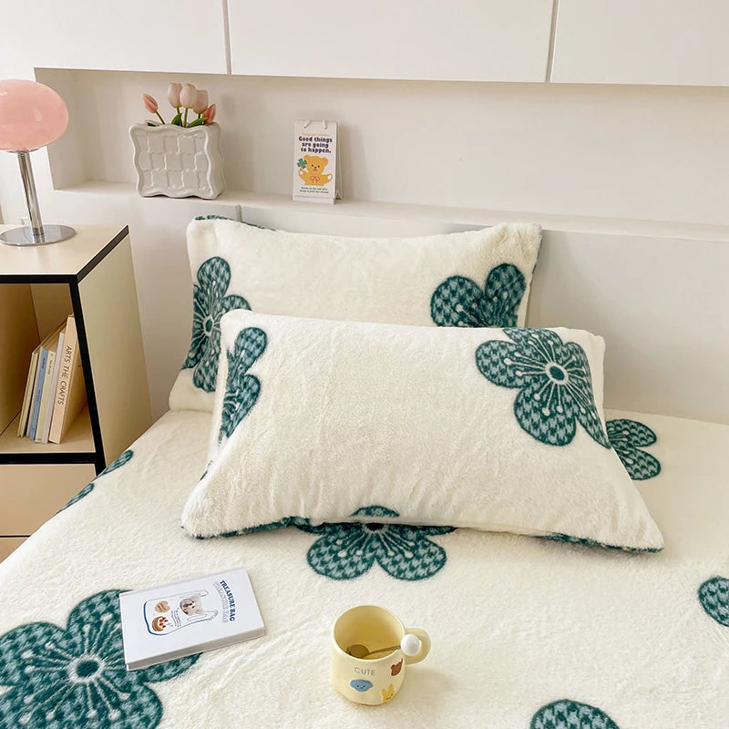 Coussins moelleux ornés de fleurs stylisées de couleur vert émeraude sur fond blanc, créant une ambiance chaleureuse et confortable dans la pièce.