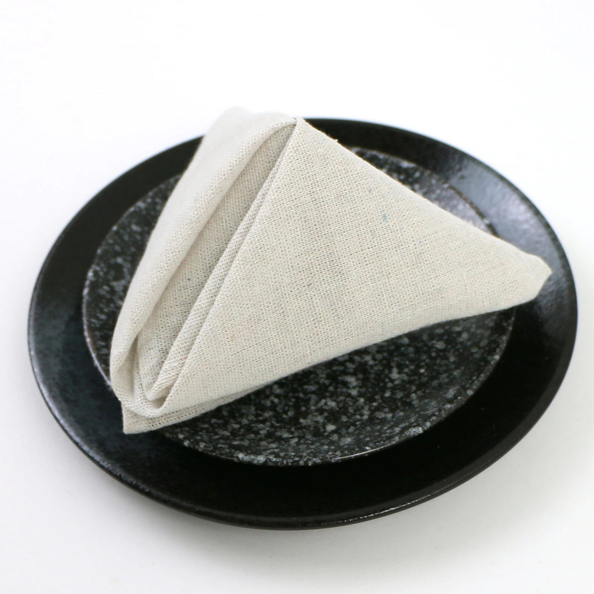 Une serviette de table de couleur crème sur une assiette de couleur noire avec un motif brillant.