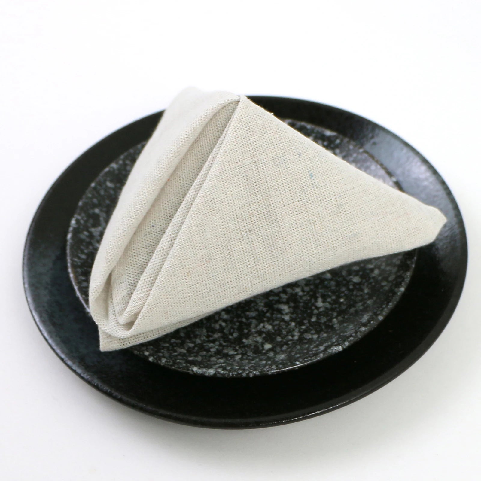 Une serviette de table de couleur crème sur une assiette de couleur noire avec un motif brillant.