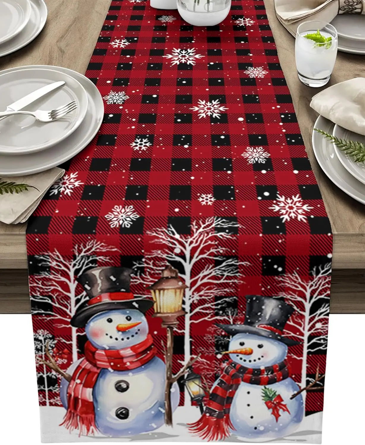 Chemin de table de Noël orné de motifs à carreaux rouges et noirs avec des flocons de neige et des bonhommes de neige portant des écharpes rouges et noires.